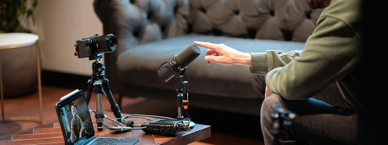 Person recording virtual presentation with laptop and microphone